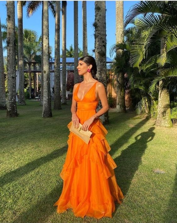 Model wearing an orange long tulle prom dress with a plunge V-neck.
