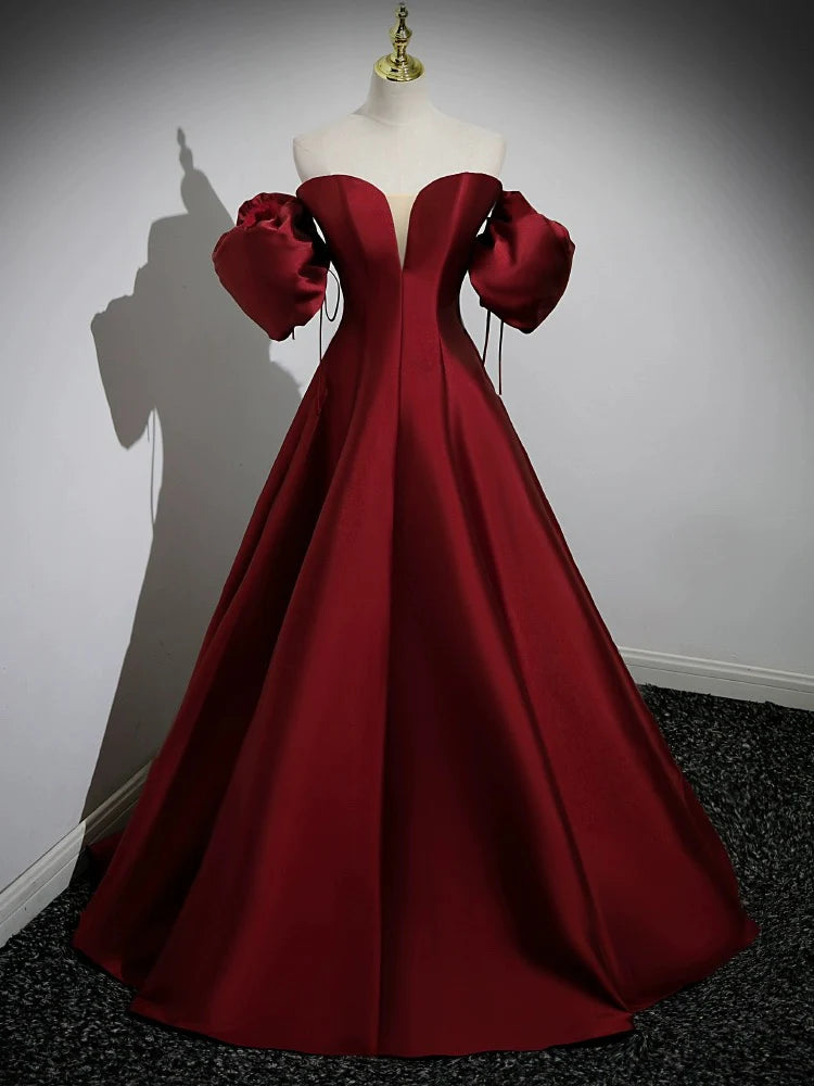 Front view of a woman wearing an elegant A-line burgundy satin long prom dress with puff sleeves.