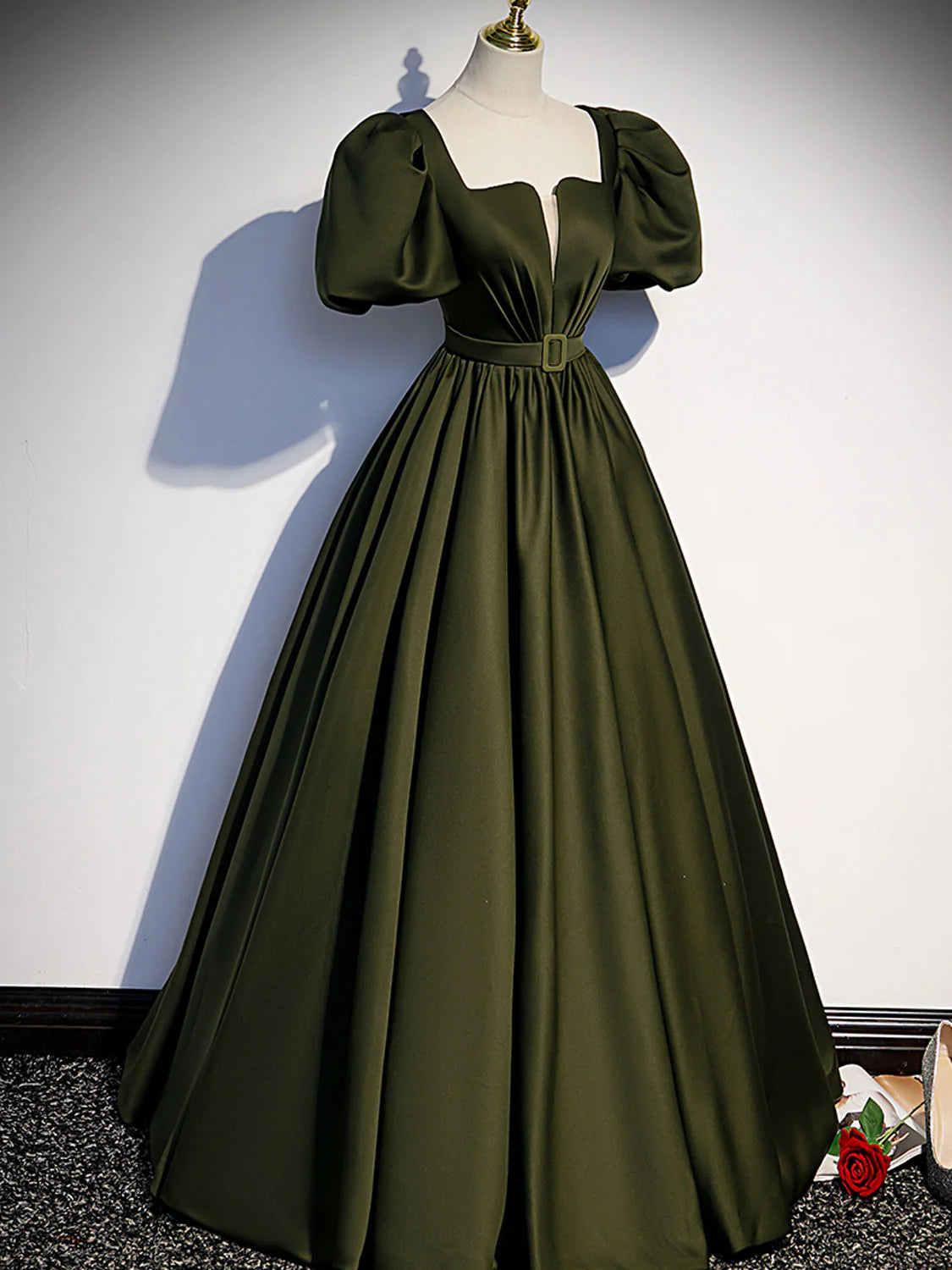 Side view of a model wearing a green satin A-line formal dress.