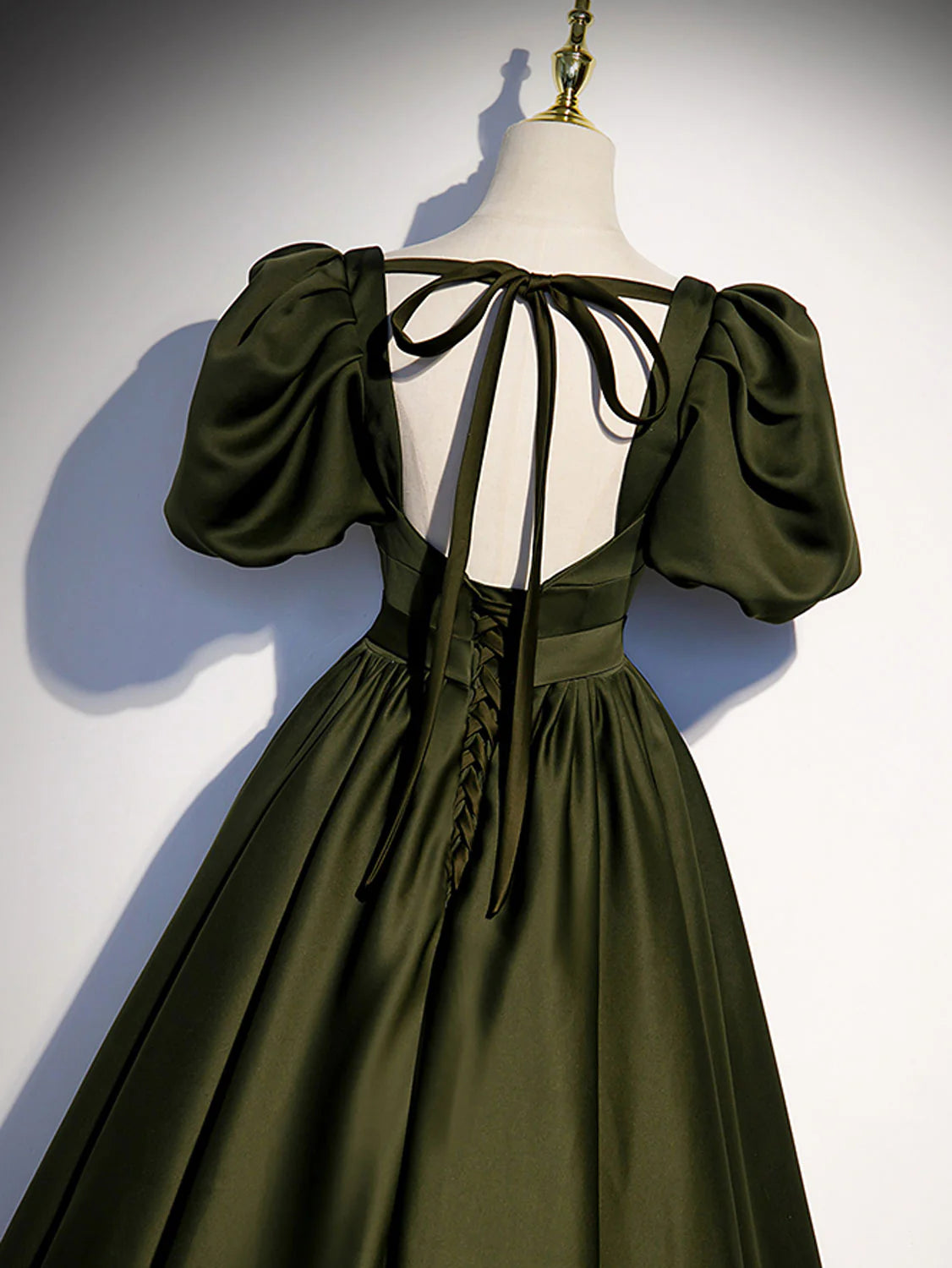 Back view of a woman in a green satin A-line ball gown.