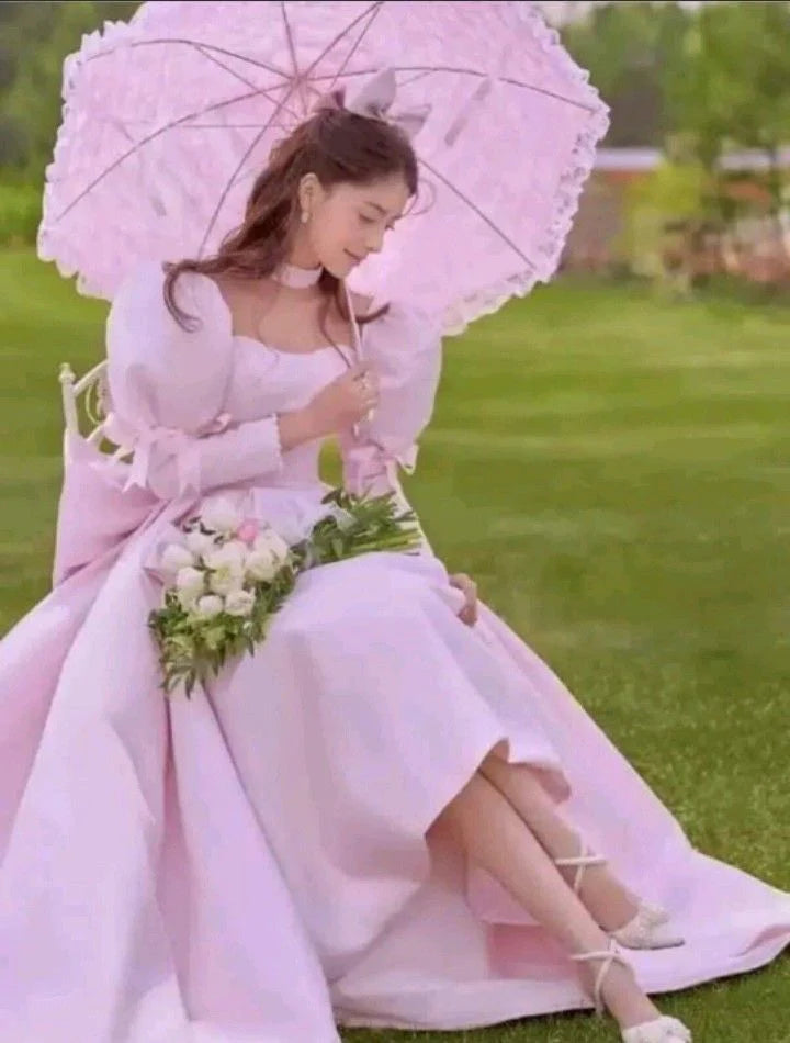 Woman wearing an elegant pink A-line long satin prom dress with puff sleeves.