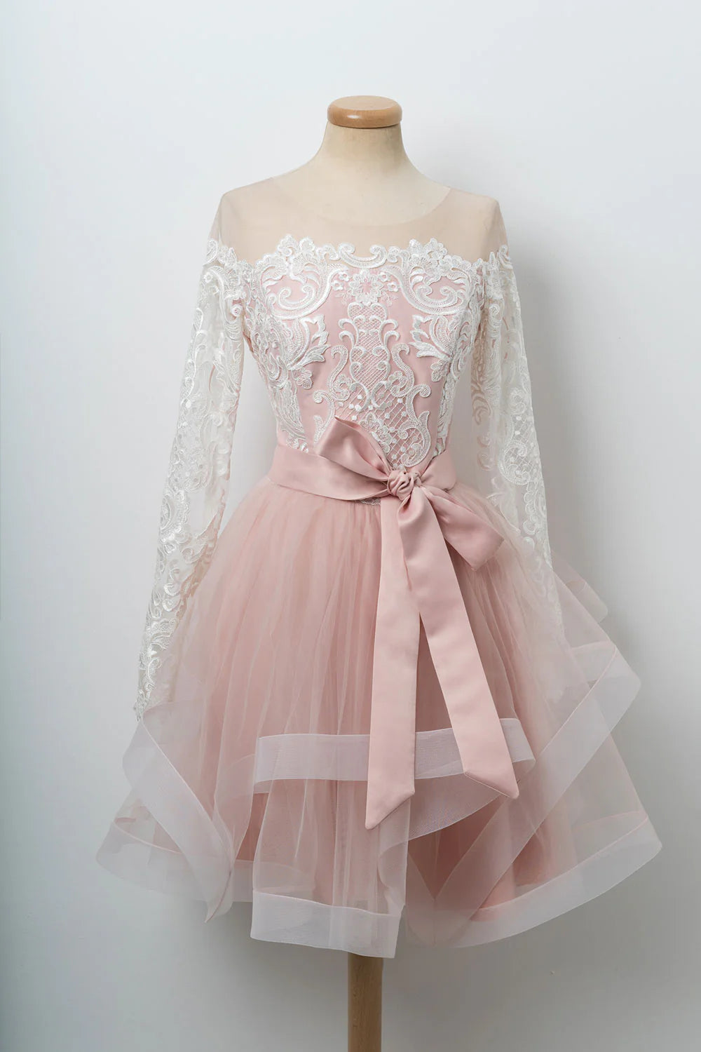 Model wearing an elegant pink short A-line homecoming dress with round neck and delicate tulle lace.