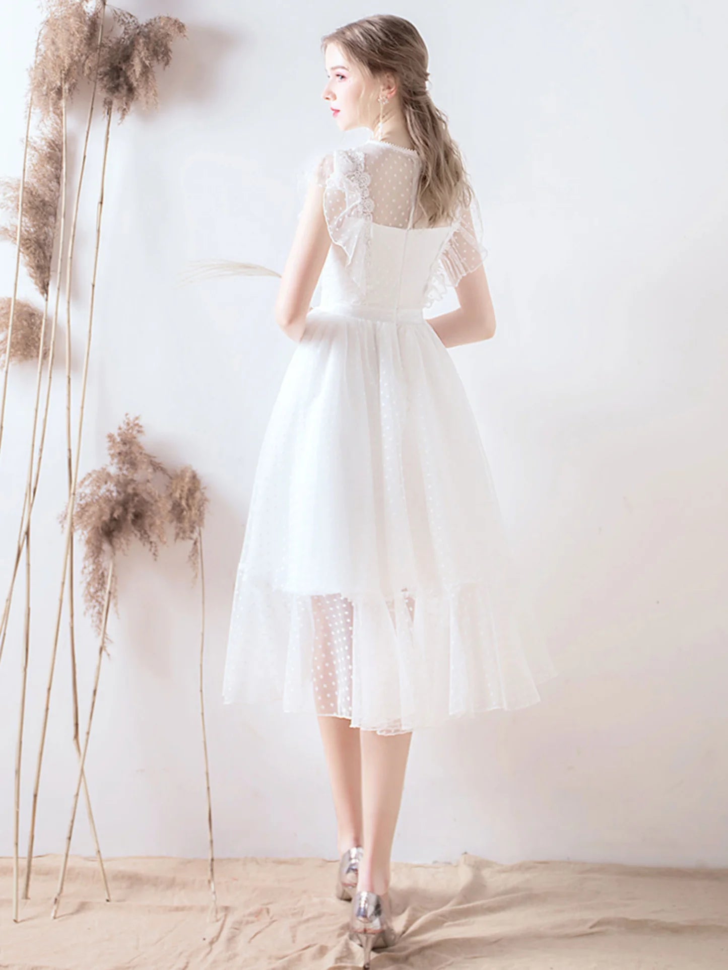 Model wearing a white short tulle and lace bridesmaid dress.