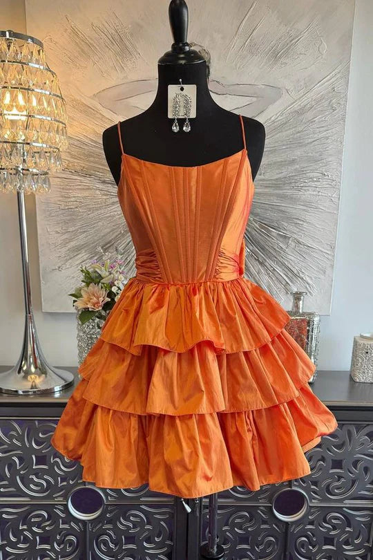 Model wearing an elegant A-line satin homecoming dress with spaghetti straps and ruffles.