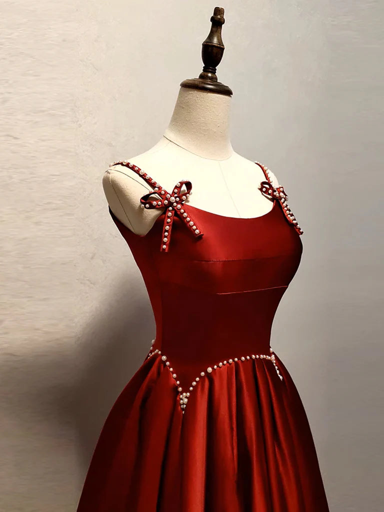 Side view of a model in a graceful A-line satin burgundy formal dress.
