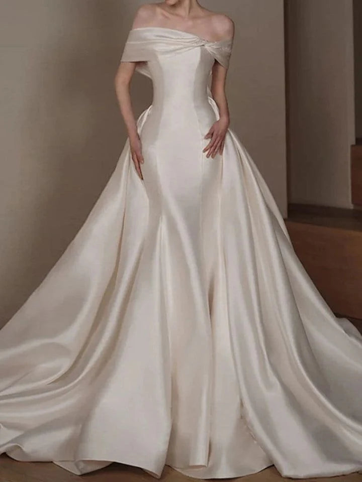 Model wearing an elegant A-line satin wedding dress with a boat neck and off-shoulder design.