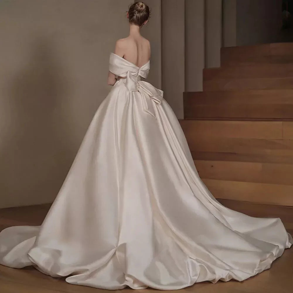 Close-up of the A-line satin wedding dress, showing the boat neck and off-shoulder detail.