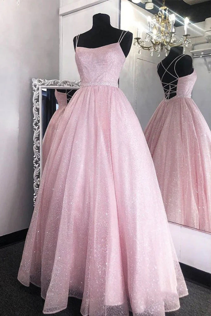 Woman wearing a long pink sequin and tulle prom dress with a fitted waist.