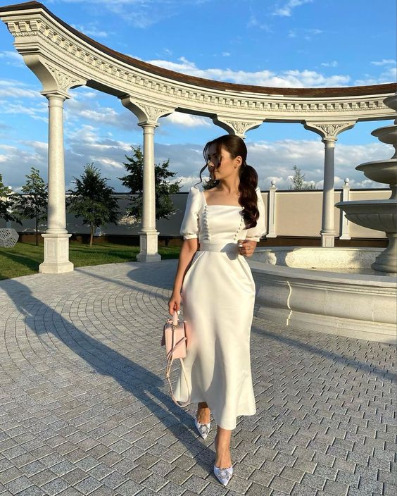 Side view of the ivory satin short sleeve evening dress, highlighting the flowing fabric.