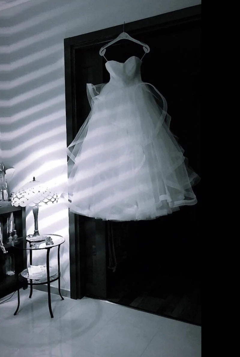 Front view of a woman wearing an elegant white tulle long prom dress with a cinched waist.