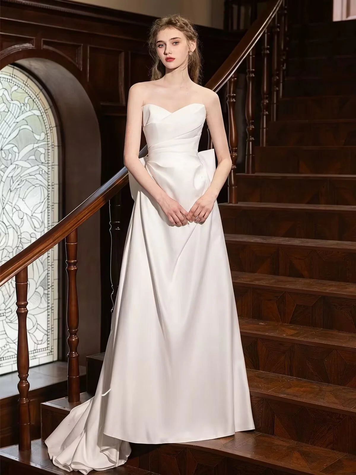 Woman wearing an elegant A-line white satin long prom dress.