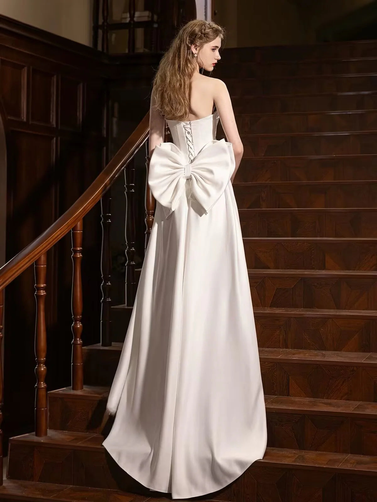 Back view of the white A-line satin formal dress with a flowing train.