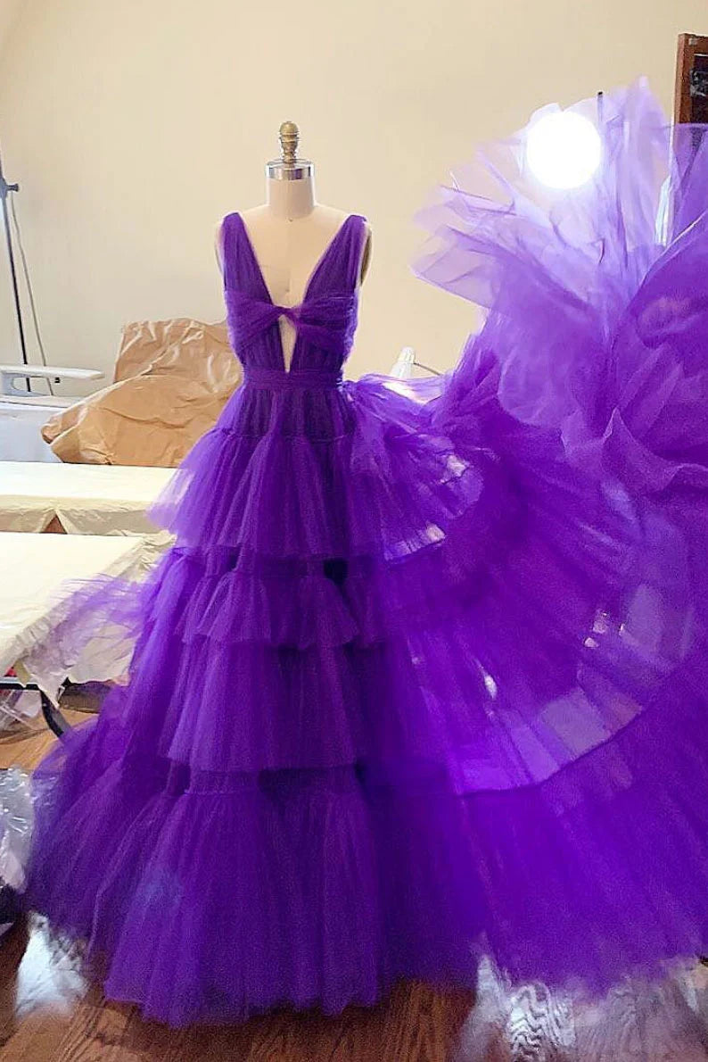 Woman wearing a long purple tulle prom dress with a flowing skirt.