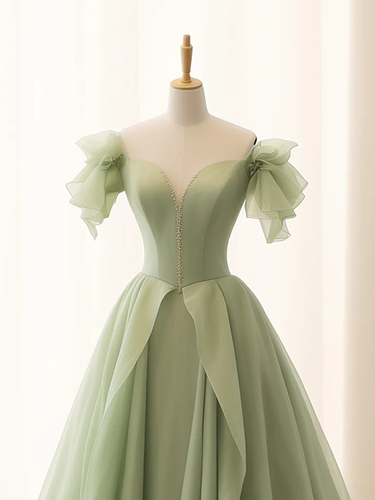 Woman in a flowing A-line green tulle long formal dress, side view.