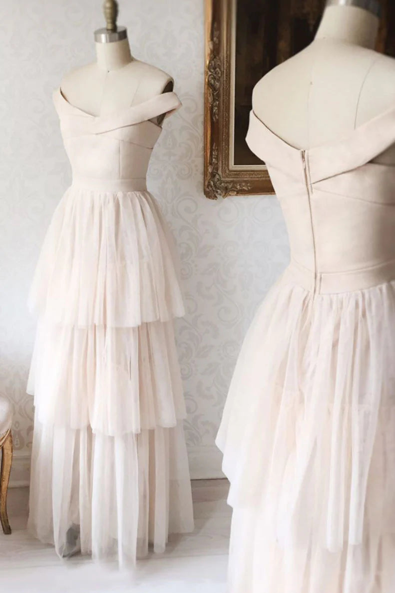 Woman wearing an elegant champagne long tulle prom dress with a fitted waist.
