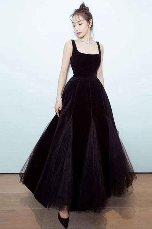 Woman wearing an elegant black A-line tulle long prom dress with a ruched waist, front view.