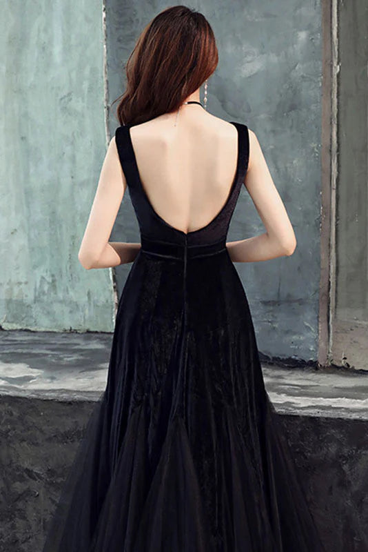 Side view of a woman in a flowing black tulle long evening dress, showcasing the skirt and cinched waist.