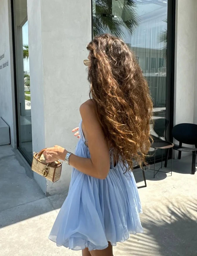 Back view of a model in a baby blue chiffon homecoming dress with an open back.