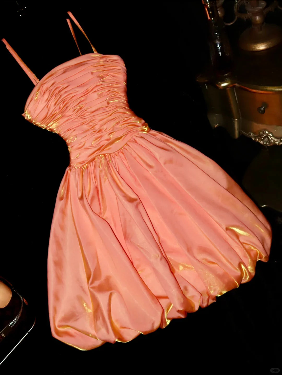 Elegant orange satin A-line homecoming dress with spaghetti straps and pleated skirt.