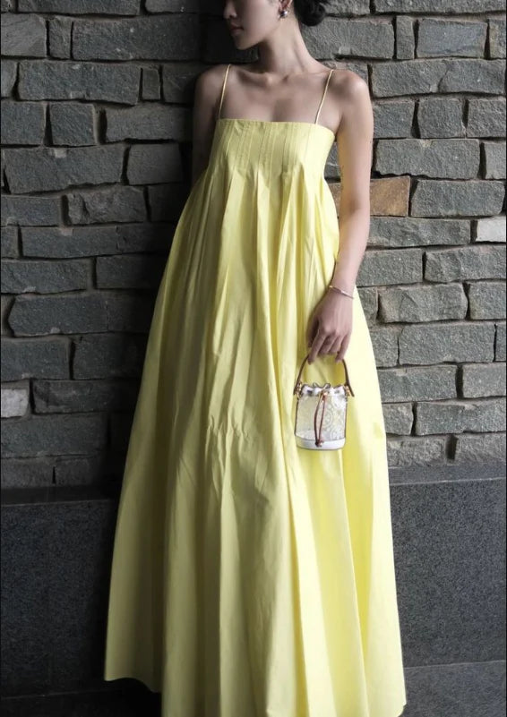 Model wearing an elegant yellow satin A-line prom dress with spaghetti straps.