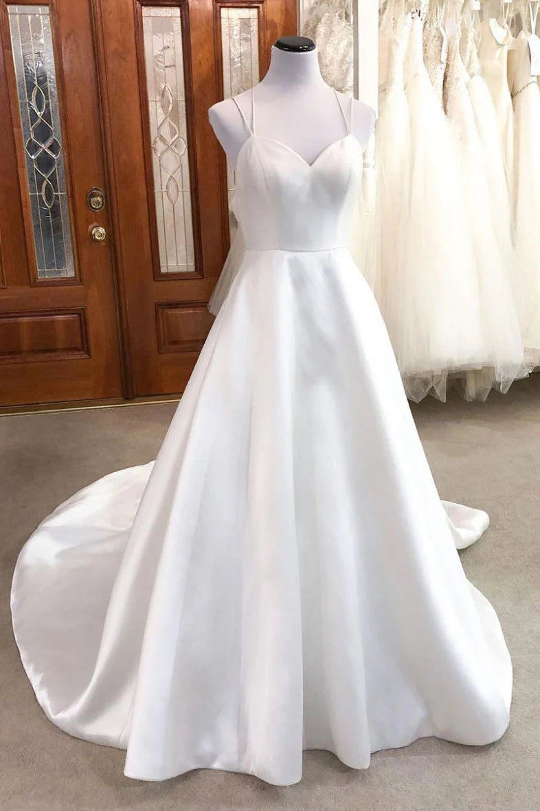 Woman wearing a white satin long prom dress with spaghetti straps.