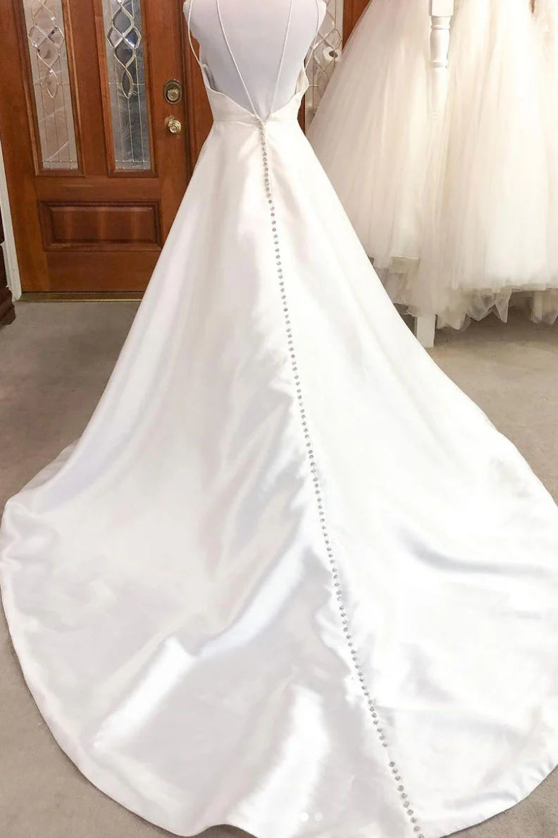 Side view of a woman in a white satin spaghetti strap evening gown.
