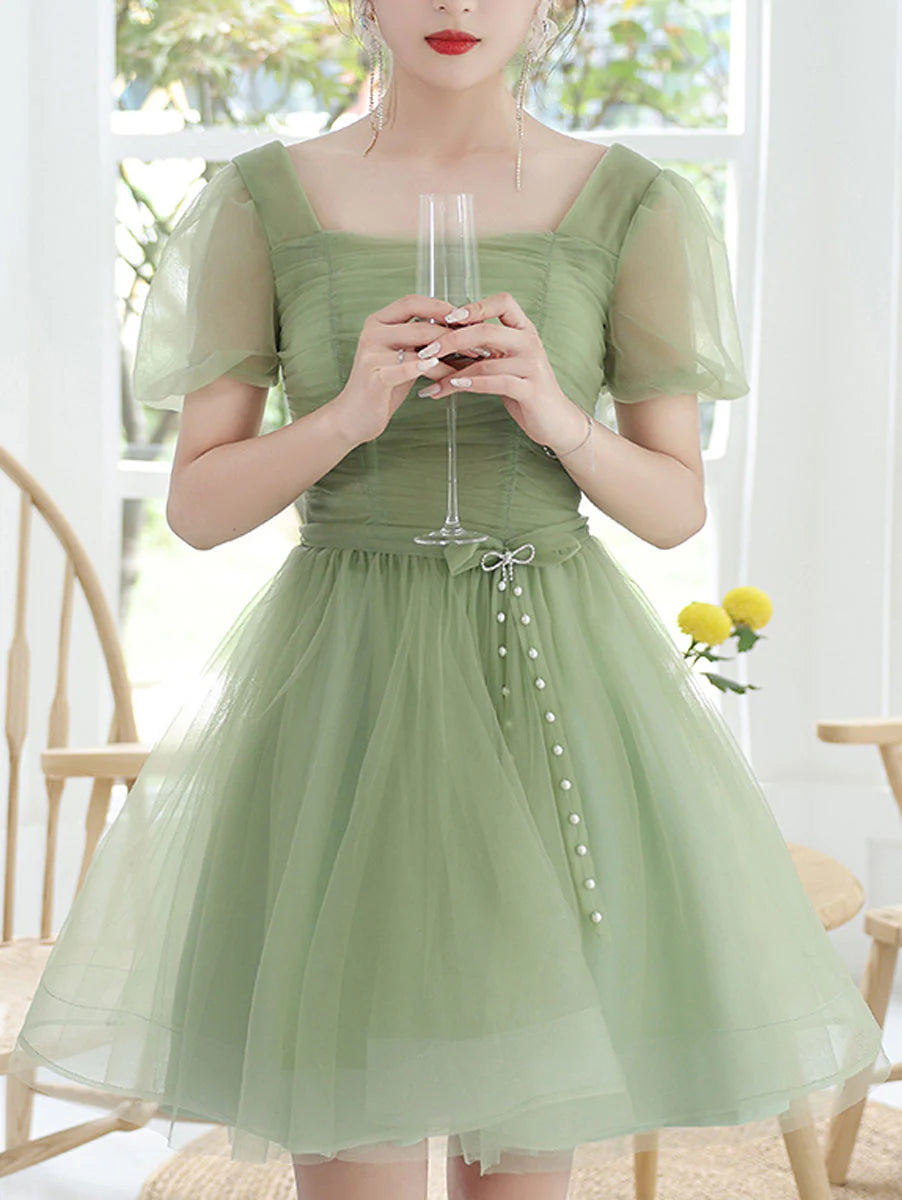Model wearing an elegant green tulle short prom dress with a square neckline.