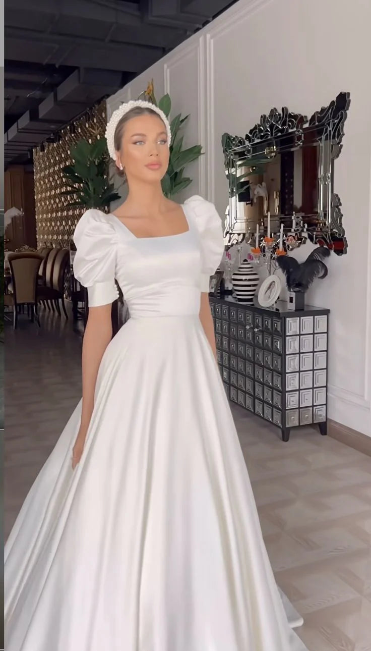 Woman wearing an elegant A-line square neck satin white long wedding dress.