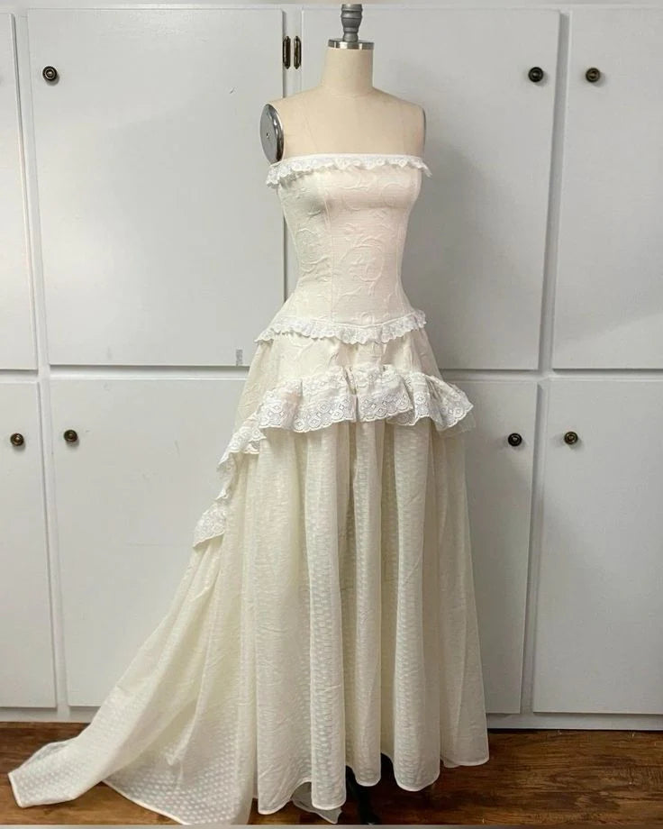 Model wearing an elegant A-line strapless ivory lace long prom dress.