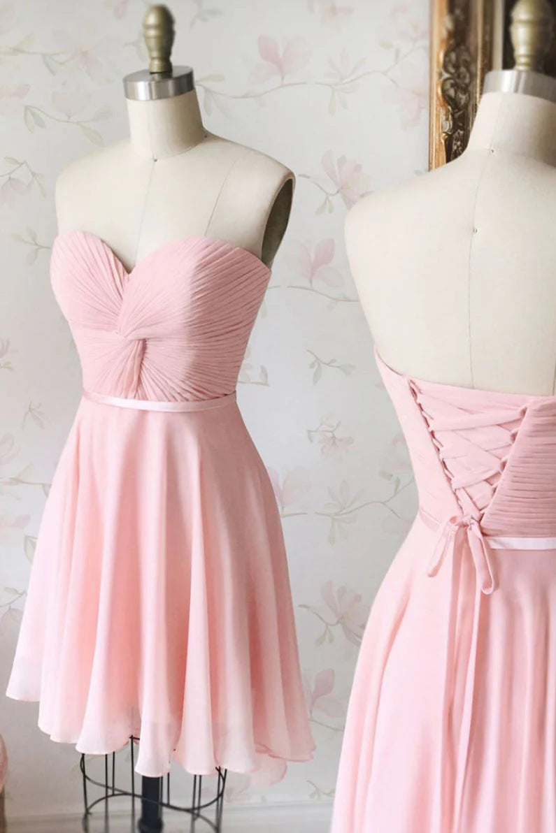 Model wearing a pink short chiffon prom dress with a sweetheart neckline.