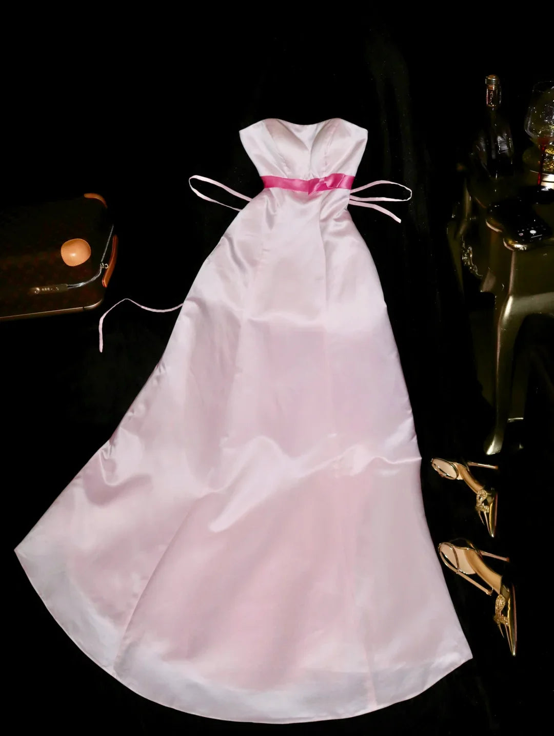 Full view of a light pink satin long party dress featuring a sweetheart neckline and a delicate bow.
