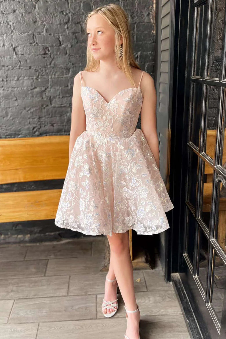 Side view of a woman in a cream lace A-line short party gown, showcasing the delicate appliques and slender straps.