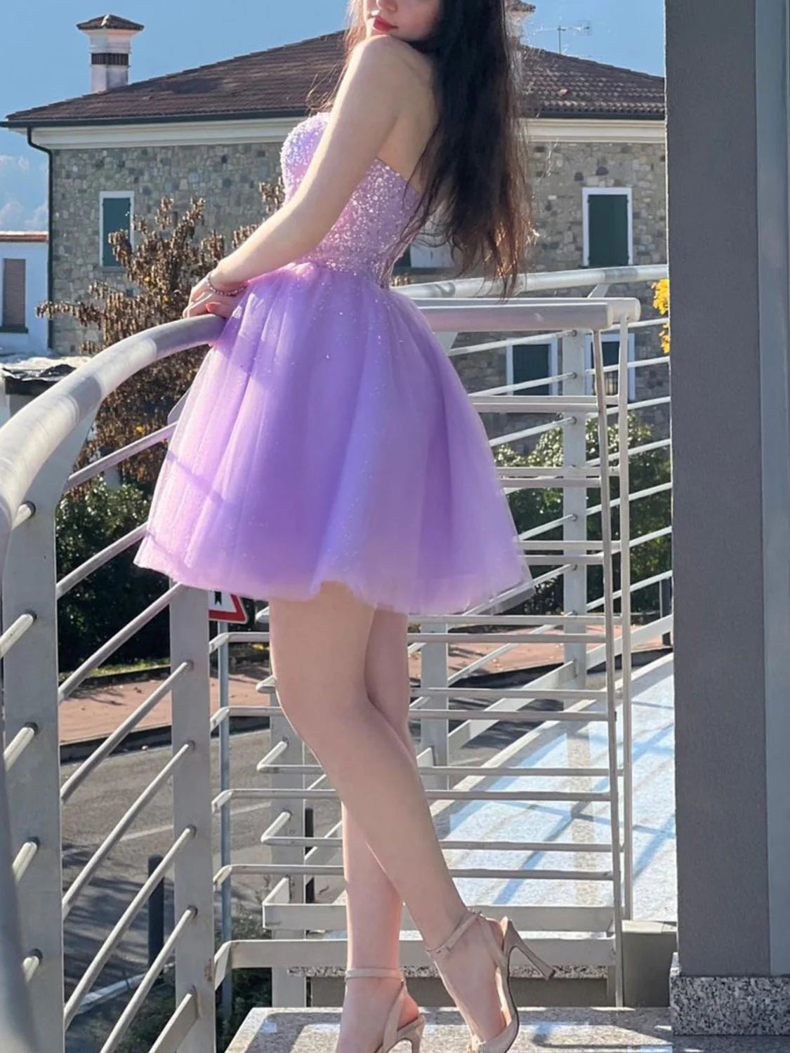 Back view of a model in a short purple off-shoulder homecoming dress, showing the elegant silhouette.