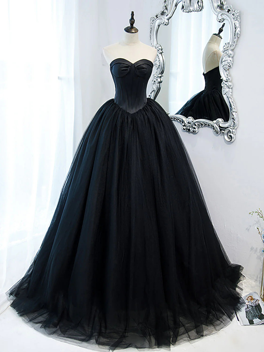Full length view of a woman in a black sweetheart neck tulle long prom dress.