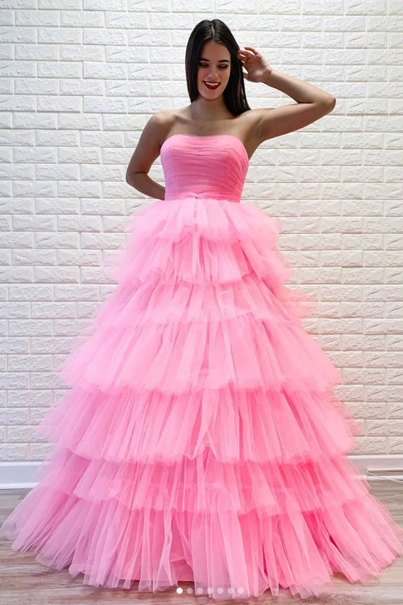 Woman posing in a flowing pink off-shoulder sweetheart tulle formal gown.