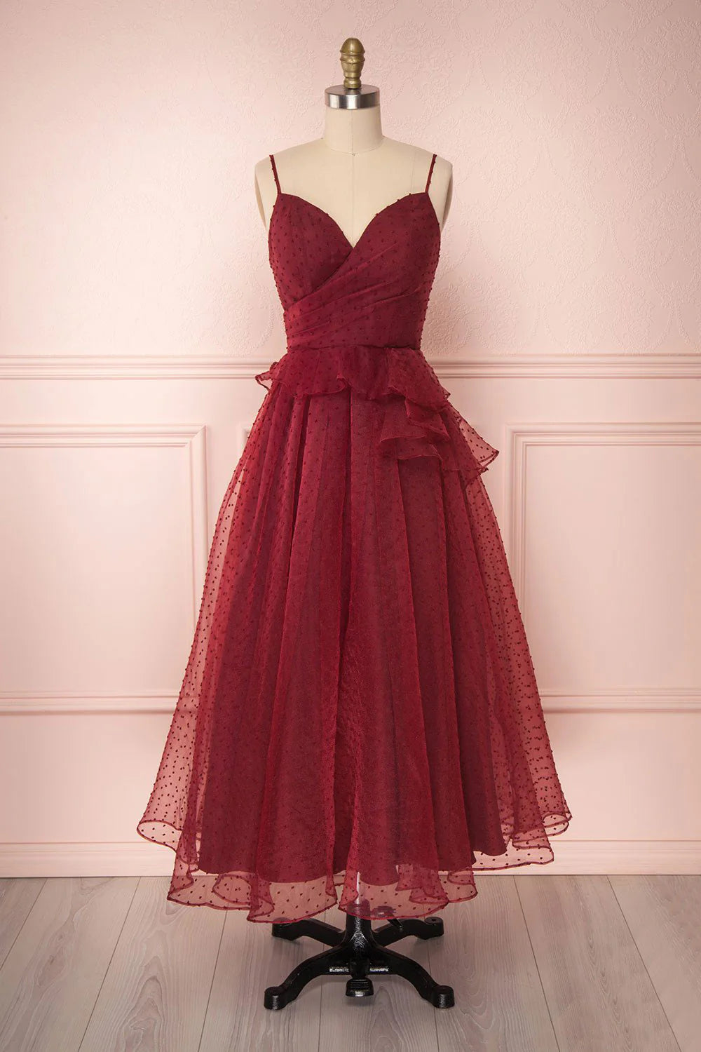 Woman wearing a burgundy A-line sweetheart tulle prom dress with a cinched waist.