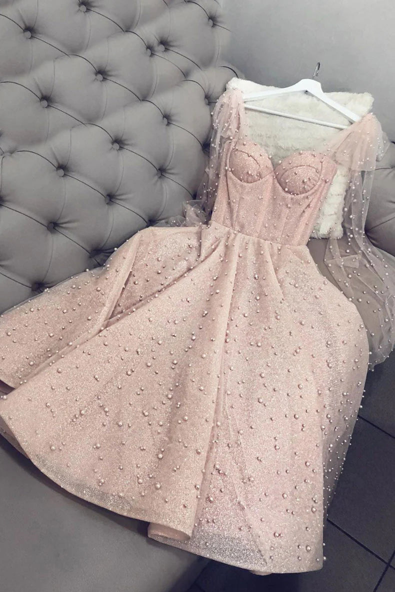 Model wearing a pink sweetheart tulle tea length prom dress with beaded details.