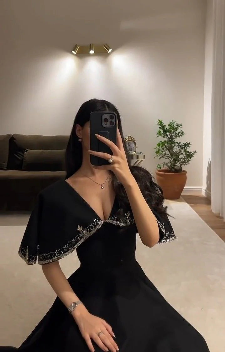 Model in an elegant black A-line beaded prom dress.