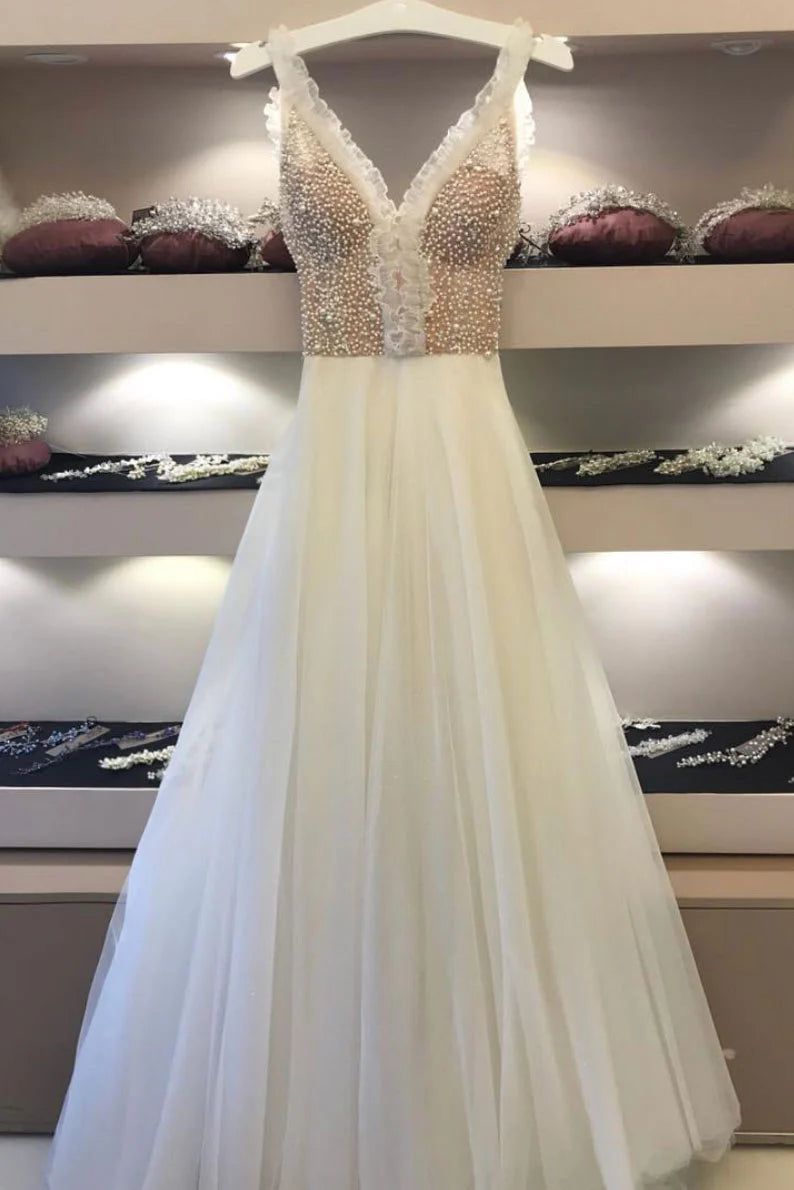Woman wearing an elegant white V-neck long prom dress with beaded tulle fabric.