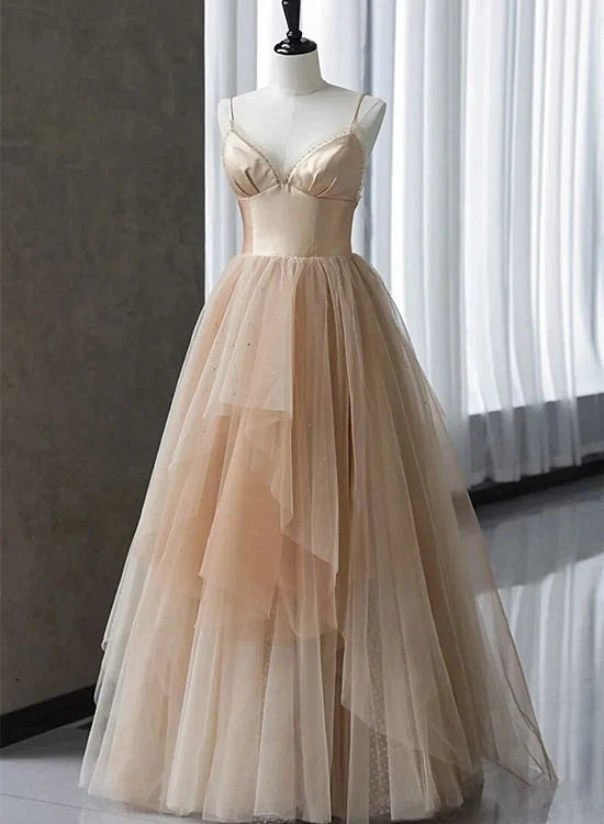 Woman wearing an elegant champagne V-neck floor-length evening dress with gradient tulle straps.