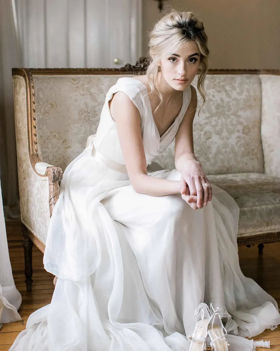 Full view of an ivory chiffon A-line dress featuring a V-neckline and delicate sash.