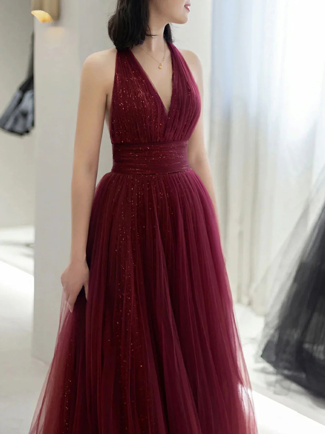 Front view of the shimmering burgundy A-line halter prom dress.