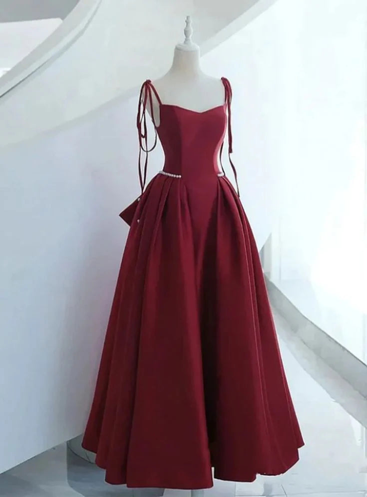 Front view of a model wearing an elegant wine red satin long formal prom dress with fashion straps.