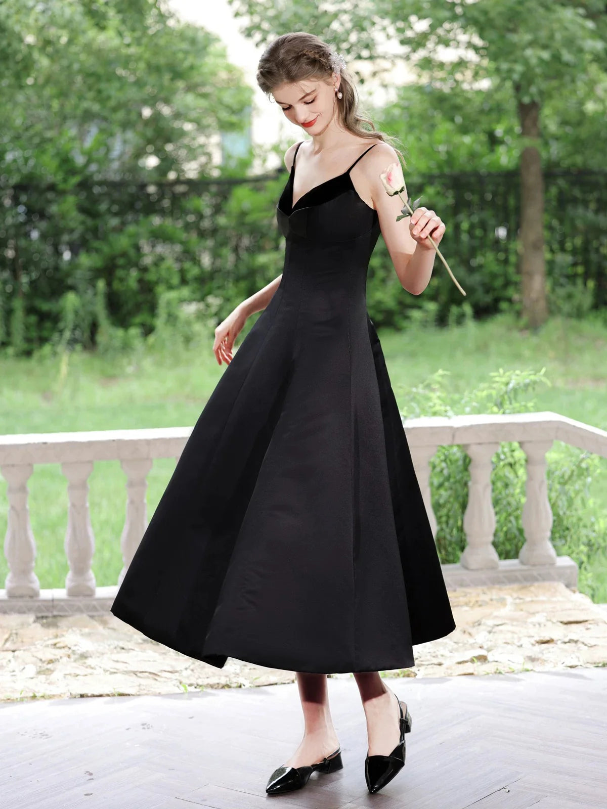 Woman in elegant black A-line V-neck tea-length satin prom dress, front view.