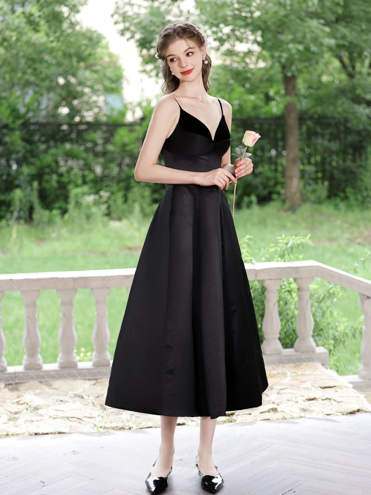 Woman in elegant black A-line V-neck tea-length satin prom dress, back view.