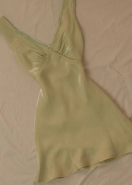 Back view of a model in a green satin waist-cinching midi dress.