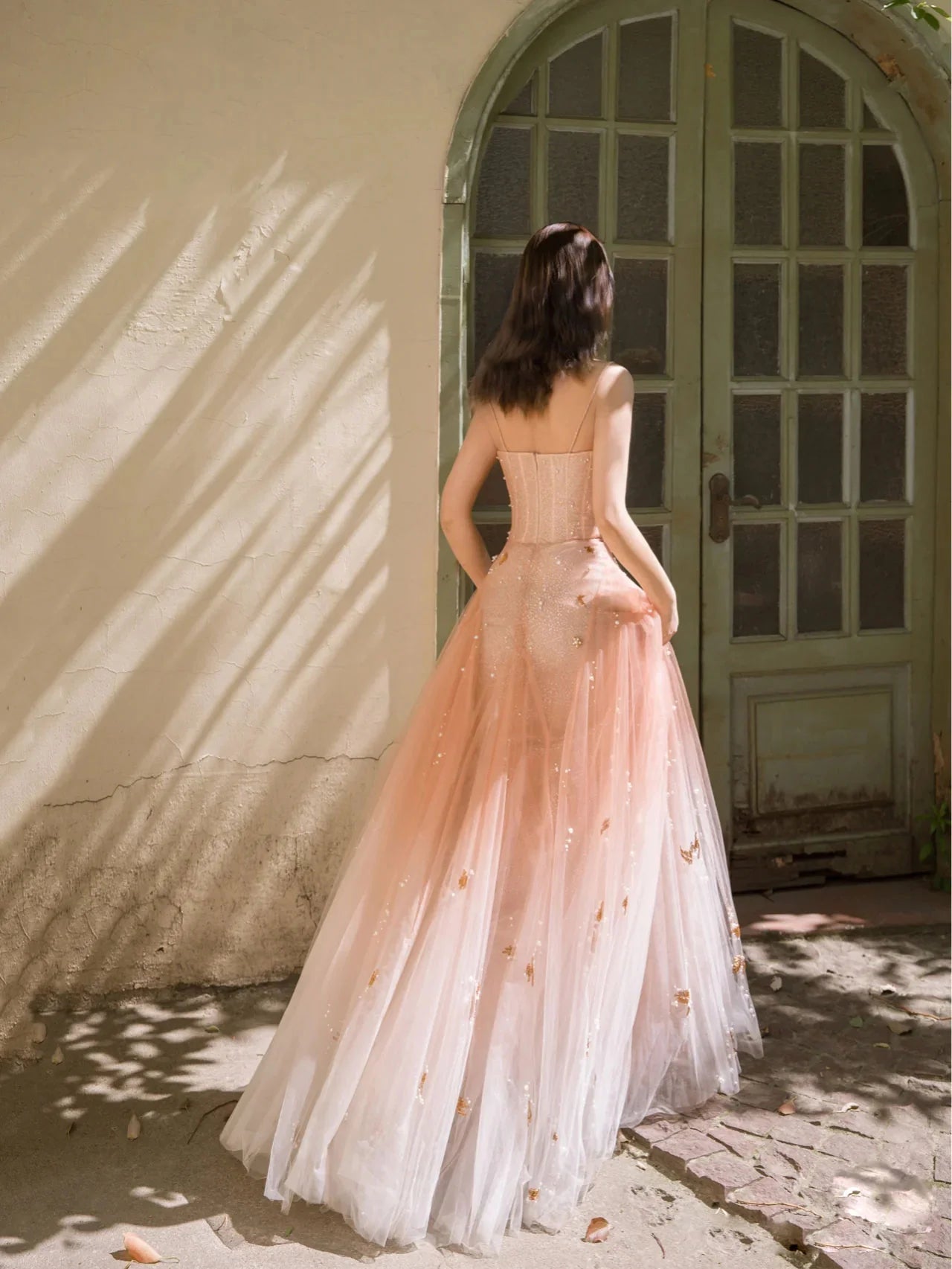 Back view of the orange pink sequin tulle V-neck long prom dress on a model.