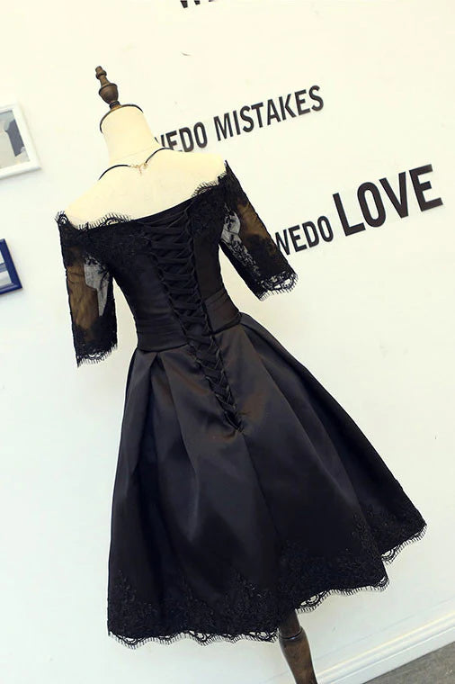 Woman wearing a black lace short homecoming dress, side view showing cinched waist.