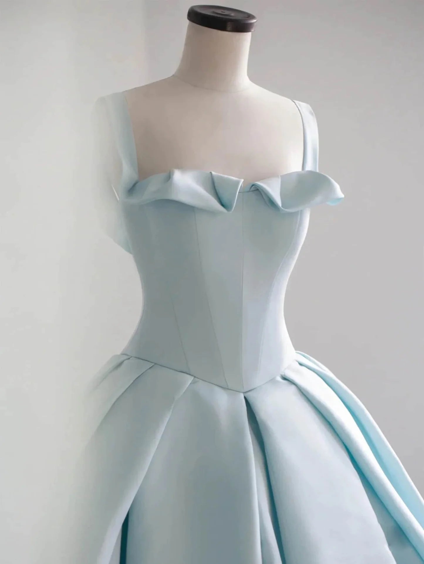 Detail of the luxurious blue satin fabric and V-neckline on the dress.