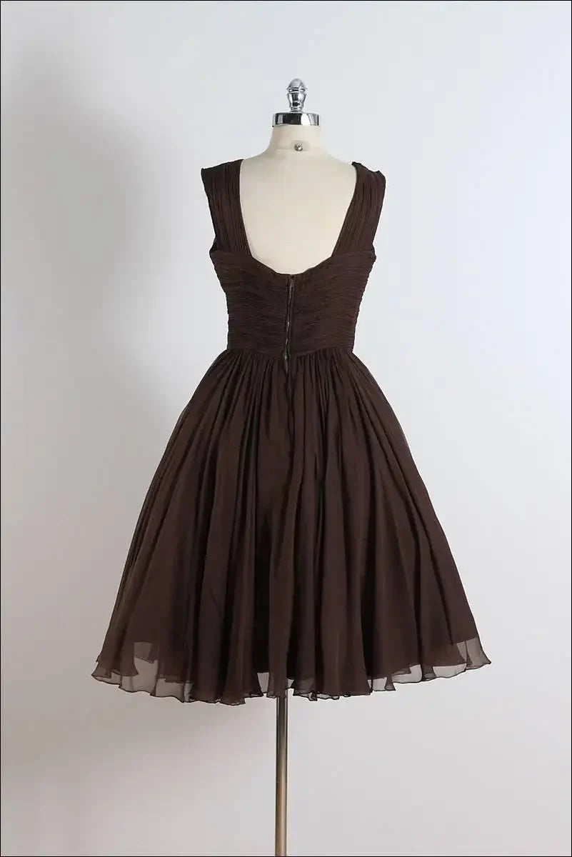 Side view of a model in a dark brown short chiffon prom dress.